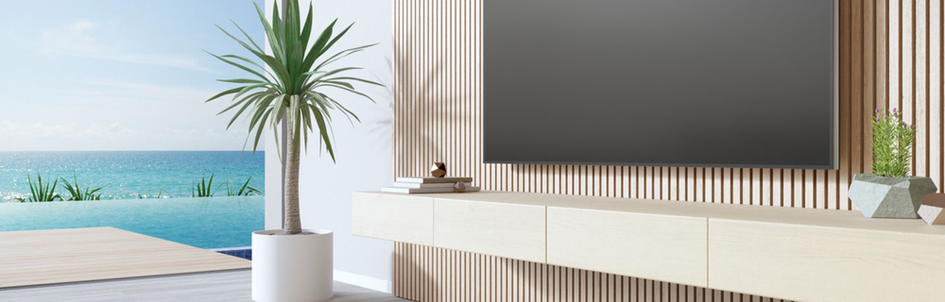 Fernseher in einem Hotelzimmer. Im Hintergrund ist ein Pool und das Meer zu sehen