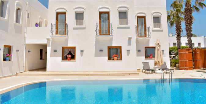 Weiße Häuserwand eines Boutiquehotels hinter einem Pool