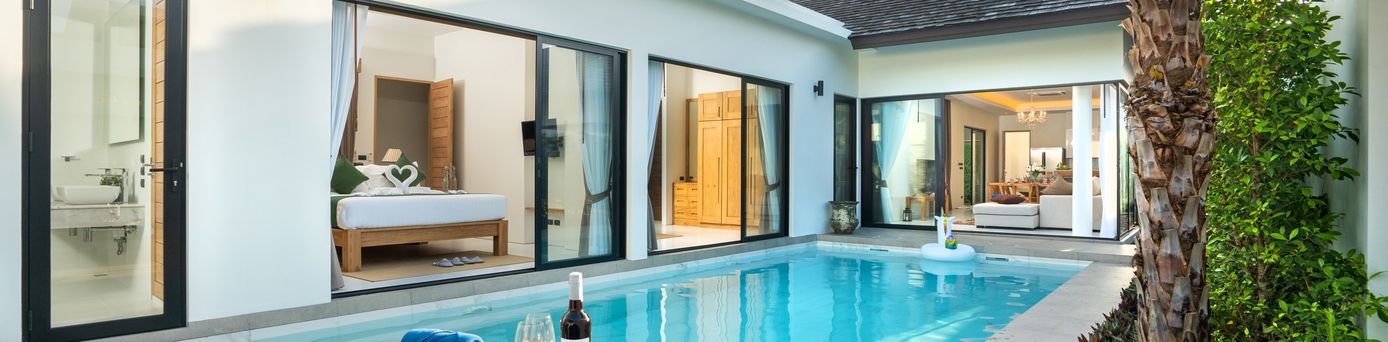 Ein Pool vor einer eleganten Villa mit zwei Liegen und einem Tisch