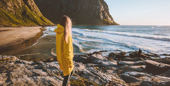 Eine Frau in einer gelben Regenjacke schaut auf das Meer