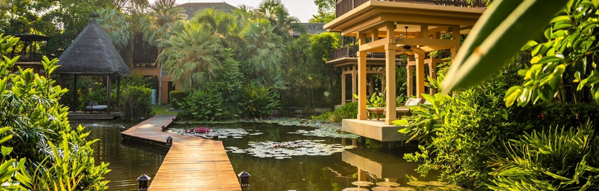 Steg der durch einen Teich mit Seerosen in einer Hotelanlage führt