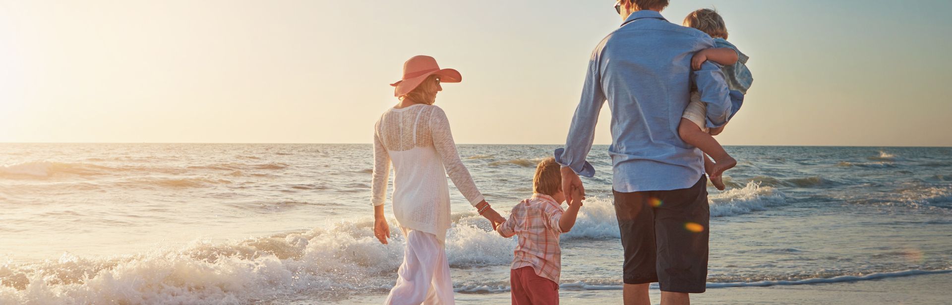 Familie, die einen Strandspaziergang beim Sonnenuntergang macht