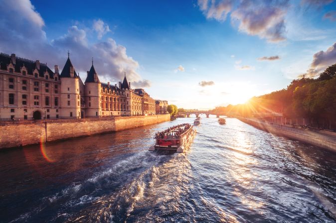 Flusskreuzfahrschiffe fahren an einer Burg entlang bei Sonnenuntergang