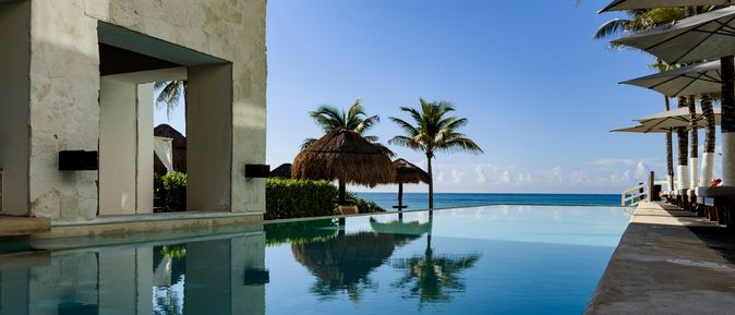 Ein Pool umgeben von Palmen und mit Blick auf das Meer