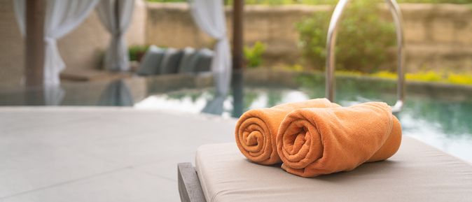 Aufgerollte Handtücher auf einer Liege am Pool