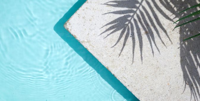 Pool von oben, auf dem Rand sieht man den Schatten einer Palme