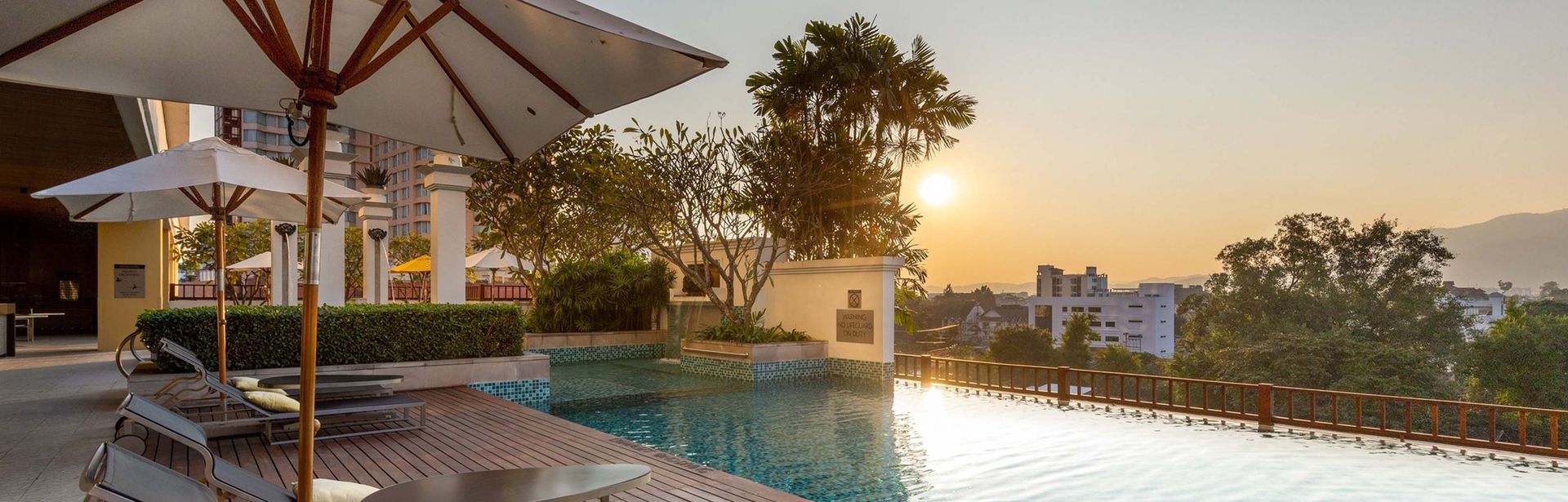 Pool mit zwei Liegen bei Sonnenuntergang