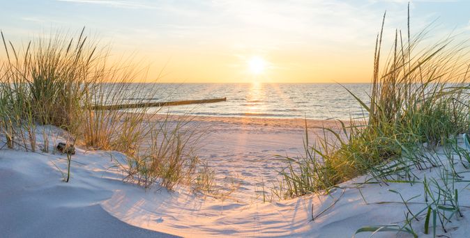 Düne mit Blick auf einen Steg und das Meer
