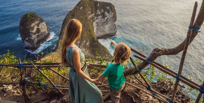 Mutter und Kind schauen von einer Treppe aus auf das Meer
