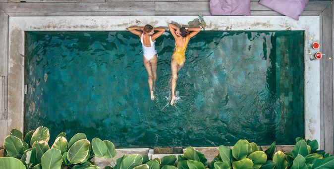 Zwei Frauen liegen im Pool und schauen sich an