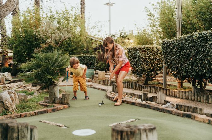 Zwei Kinder spielen Minigolf in einem Clubhotel