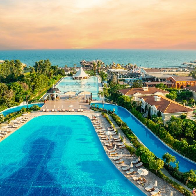 Zwei große Pools umgeben von Bäumen und mit Blick auf das Meer