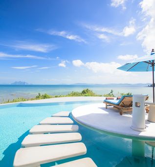 Ein Tisch mit kleinem Sonnenschirm und Getränken steht im Pool