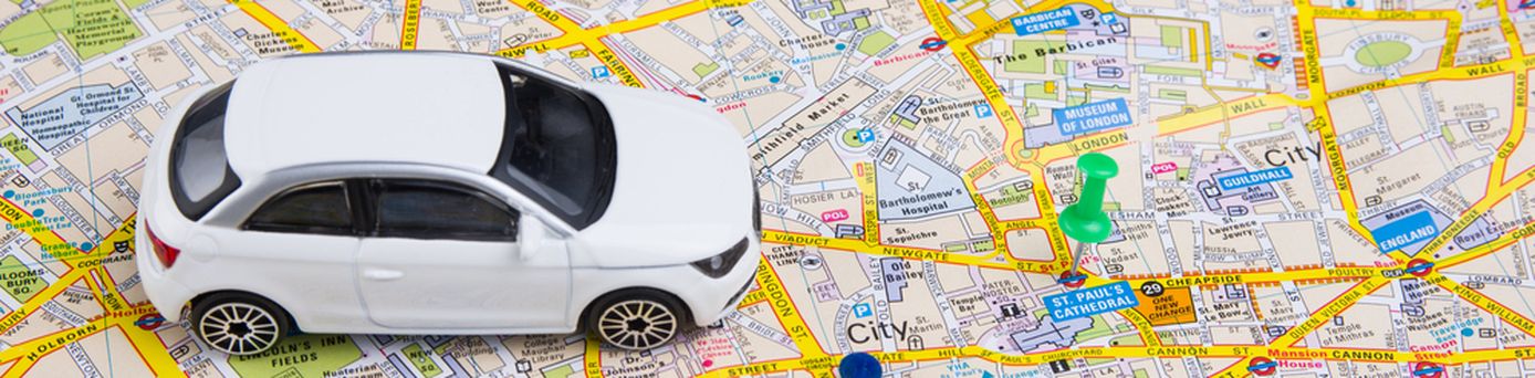 Ein Miniaturauto steht auf einer Stadtkarte von London. Daneben zwei Reißzwecken