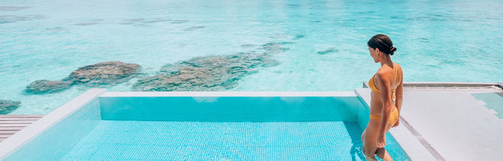 Eine Frau steigt in einen erhöht über dem Strand gelegen Pool