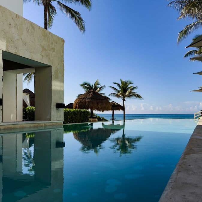 Ein Pool umgeben von Palmen und mit Blick auf das Meer