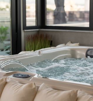 Whirlpool der blubbert und in den Wasser eingelassen wird. Vor dem Whirlpool ist eine Reihe von Kissen