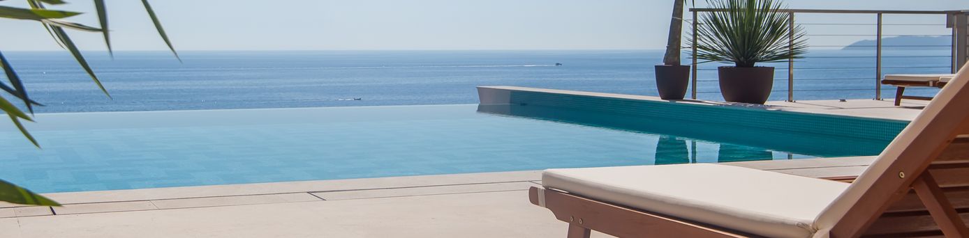 Eine Liege und an einem Infinity Pool, im Hintergrund das Meer