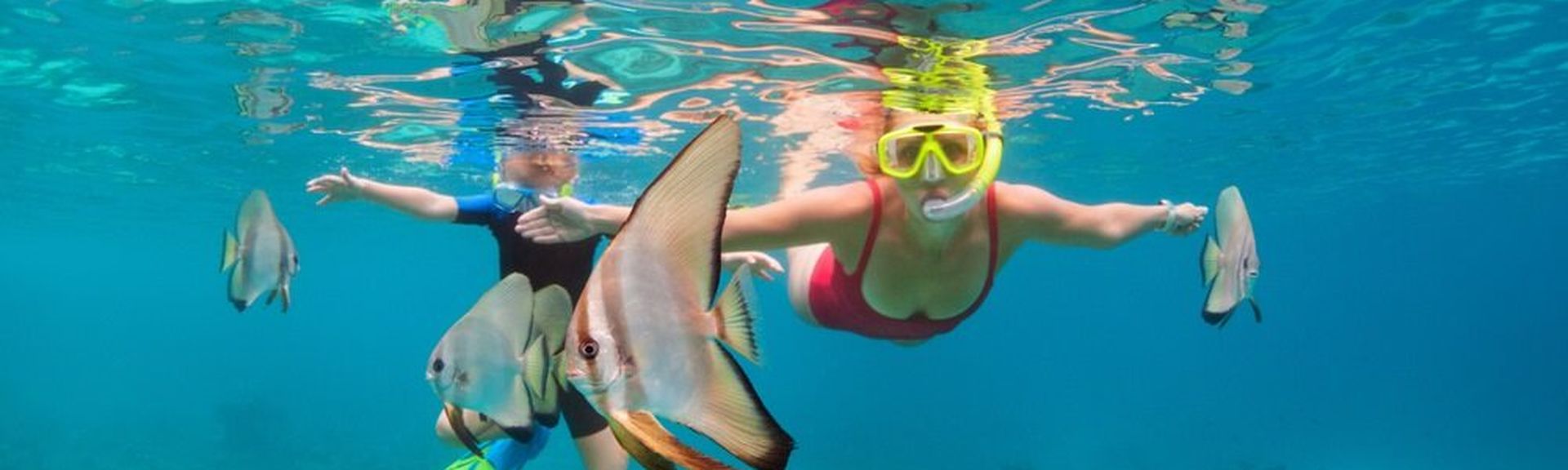 Zwei Kinder tauchen mit Taucherbrille und Schnorchel zwischen Fischen