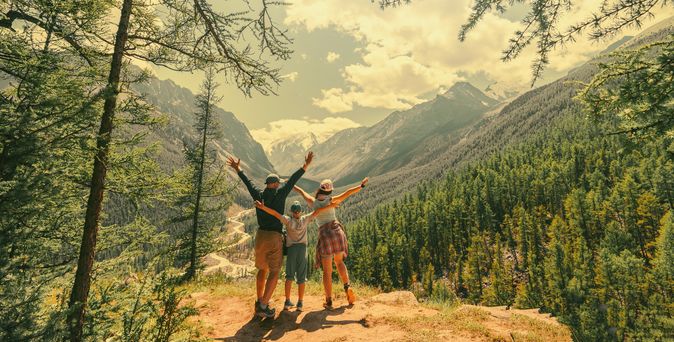 Eltern und Kind schauen beim Wandern gemeinsam auf eine Berglandschaft 