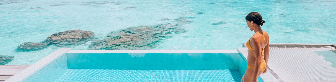 Eine Frau steigt in einen erhöht über dem Strand gelegen Pool