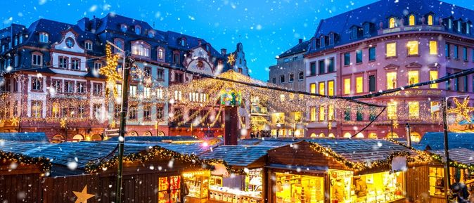 Hell erleuchtete Buden eines Weihnachtsmarktes mitten in einer Stadt