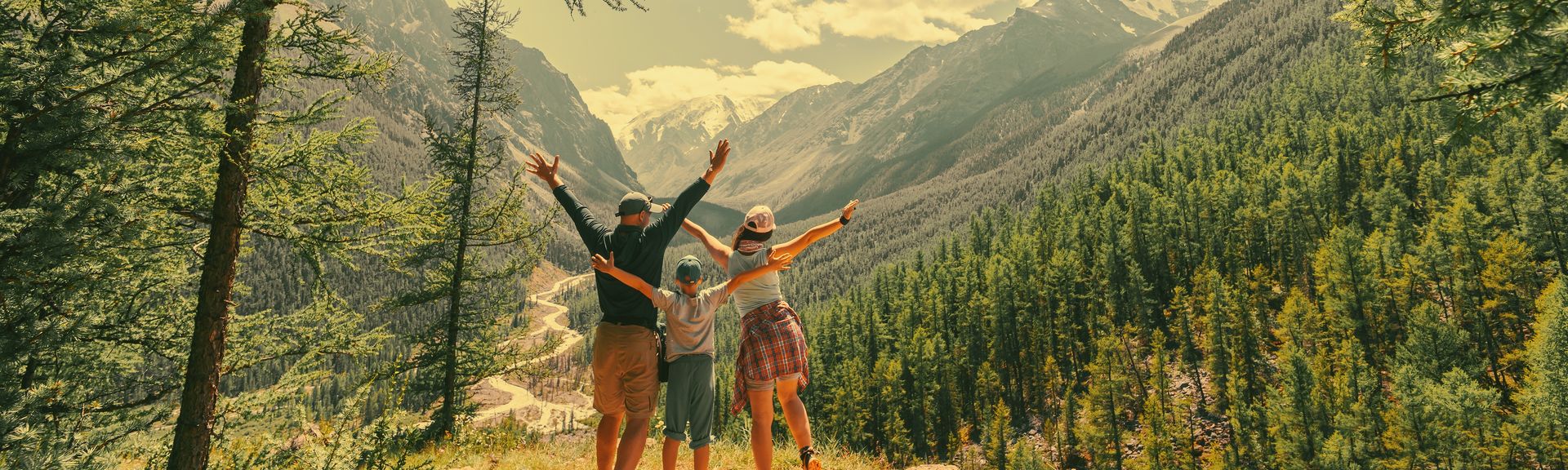 Eltern und Kind schauen beim Wandern gemeinsam auf eine Berglandschaft 