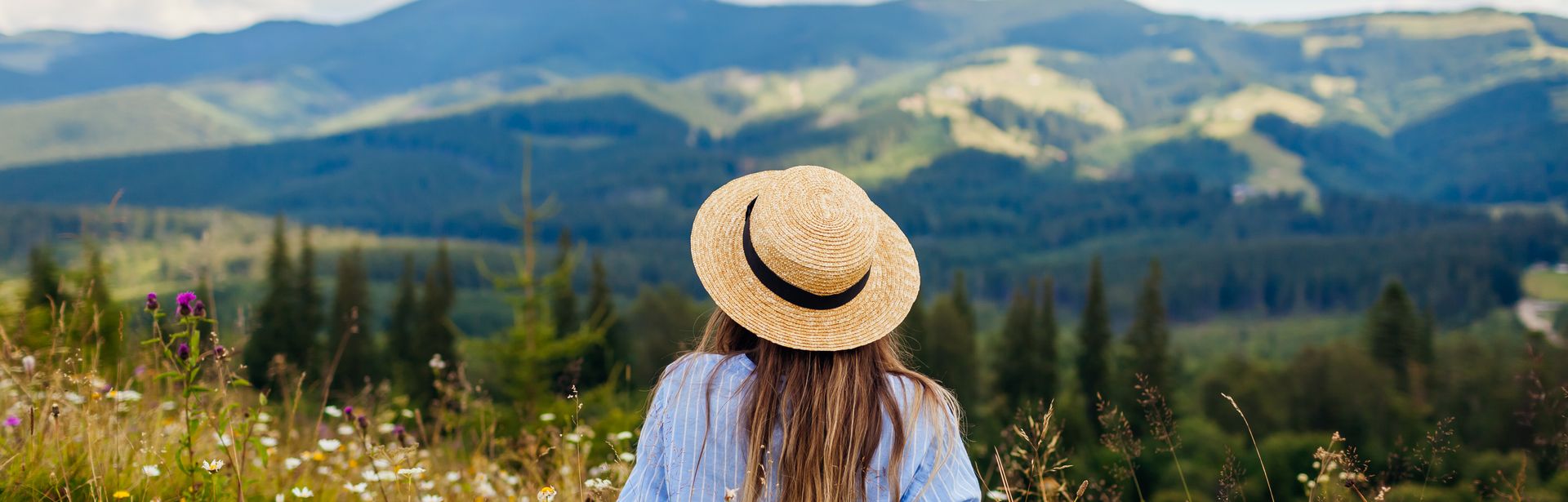 Frau liegt im Gras umgeben von einer Berglandschaft