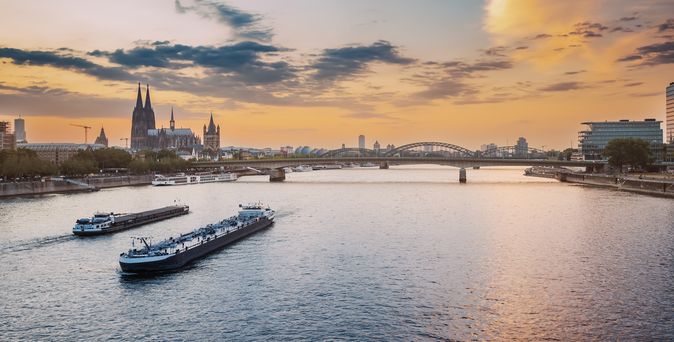 Zwei Flusskreuzfahrschiffe auf einem Fluss, der durch eine Stadt fließt 