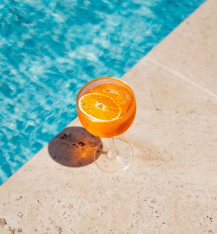Ein Oranges Getränk steht am Rand eines Pools