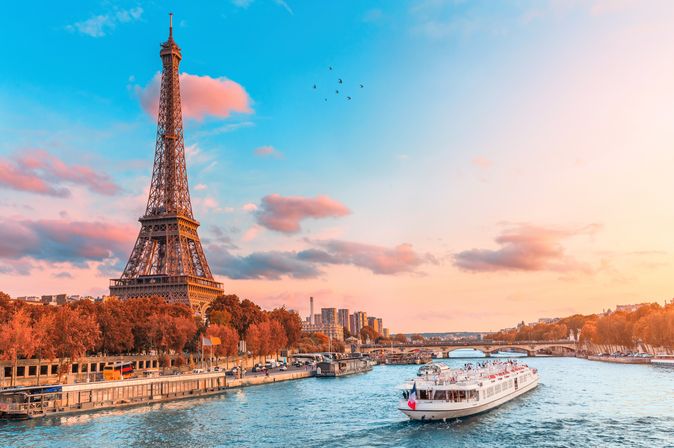 Flusskreuzfahrtschiff auf der Seine neben dem Eiffelturm in Paris