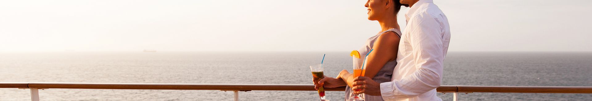 Ein Paar steht auf einem Kreuzfahrtschiff an der Reling und schaut aufs Meer