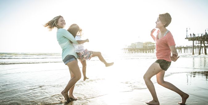 Eine Familie am Strand, Mutter hebt Ihre Tochter lachend hoch