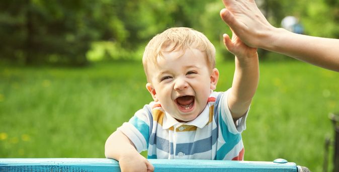Lachender Junge gibt einem Erwachsenden ein High-Five