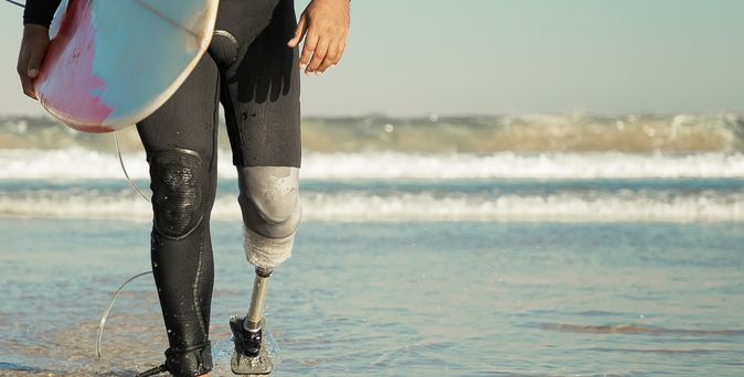 Surfer mit Beinprothese am Strand 
