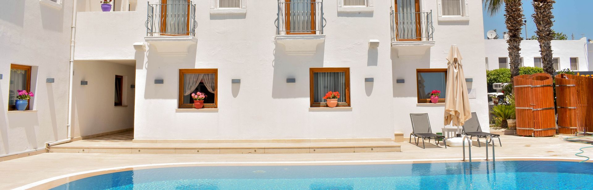Weiße Häuserwand eines Boutiquehotels hinter einem Pool