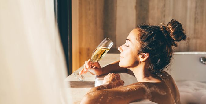 Eine Frau lehnt am Rand eines Whirlpools und genießt ein Glas Sekt