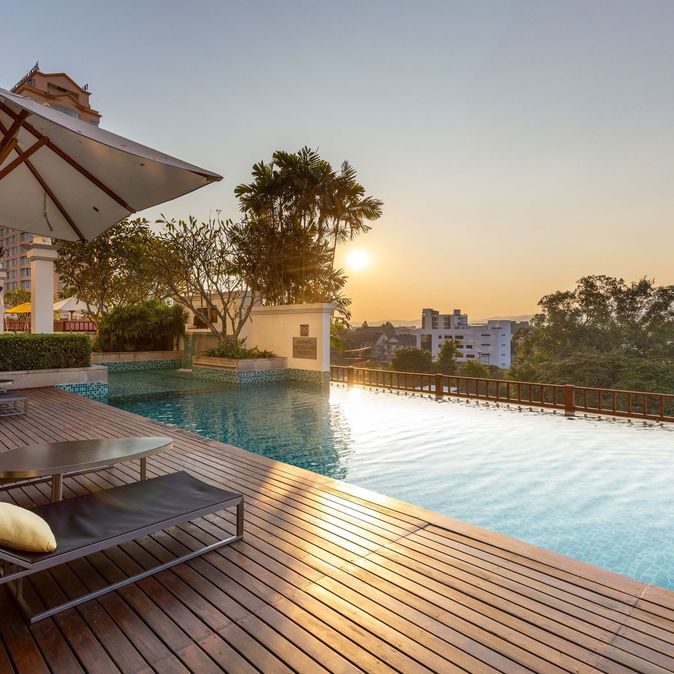 Pool mit zwei Liegen bei Sonnenuntergang