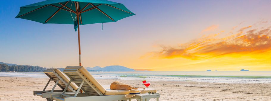 Zwei Liegen mit Sonnenschirm stehen am Strand