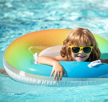 Ein Kind mit einer Sonnenbrille in einem bunten Poolring