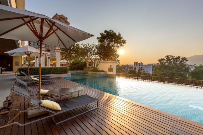 Hotelpool bei Sonnenuntergang mit Liegen und einem Sonnenschirm