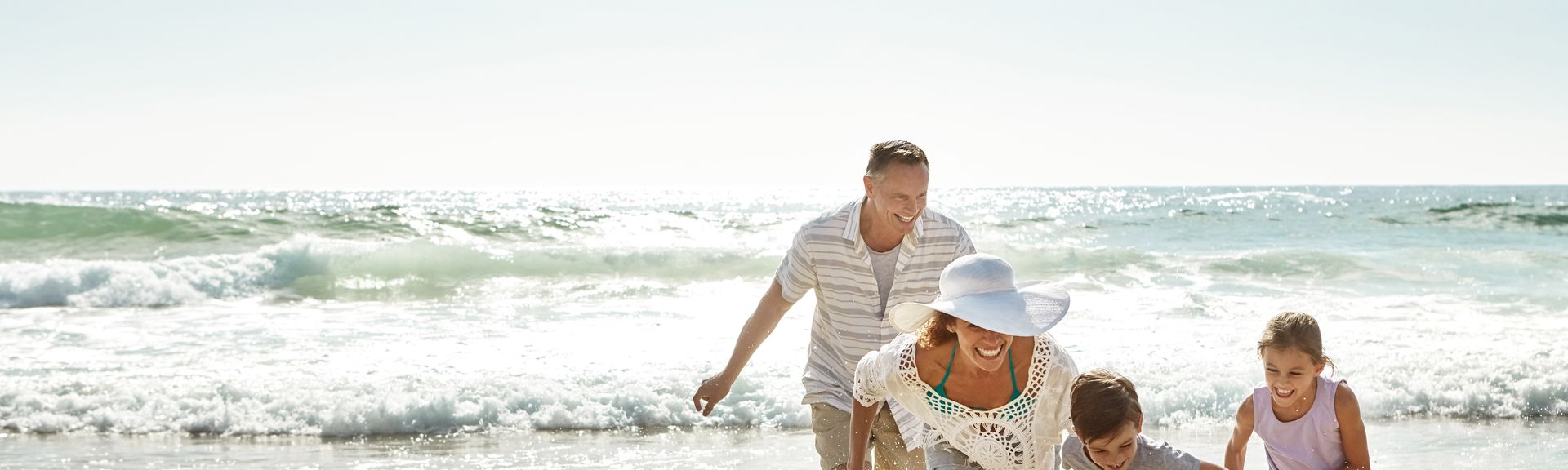 Eine Familie am Strand läuft lachend durch das Wasser
