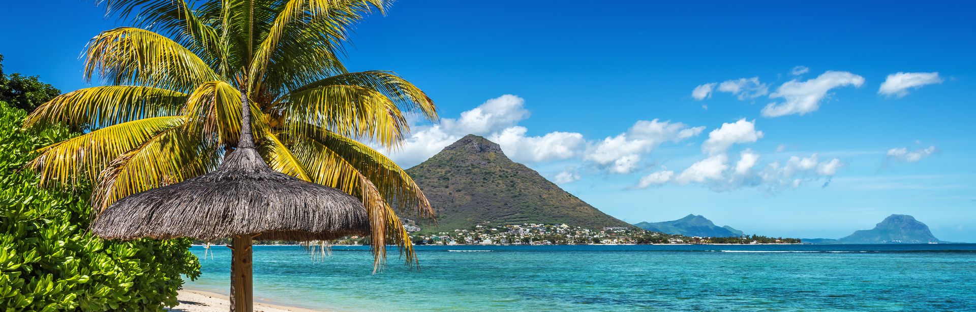 Zwei Liegen unter einem Schirm am Strand