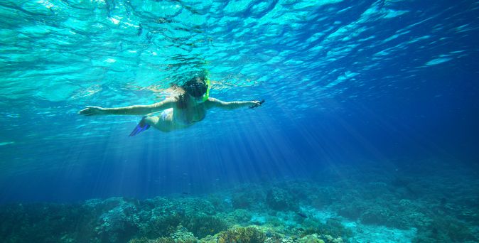 Ein Kind mit Schnorchel im Meer breitet die Arme aus
