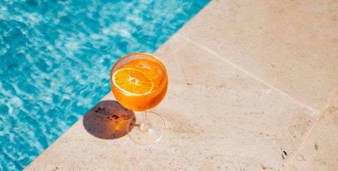 Ein Oranges Getränk steht am Rand eines Pools