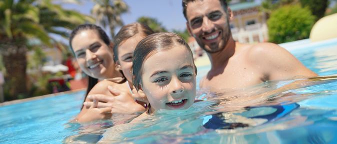 Eine Familie in einem Pool lächelt in die Kamera