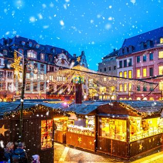 Hell erleuchtete Buden eines Weihnachtsmarktes mitten in einer Stadt