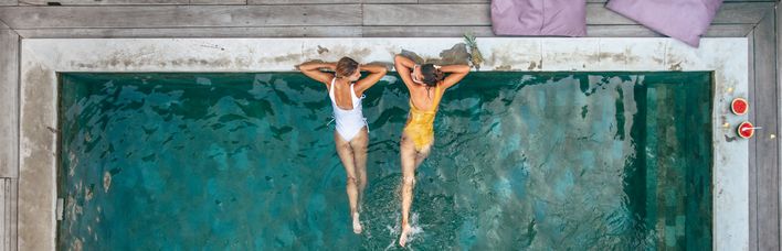 Palmen Pool und Liegestühle vor türkisblauem Meer
