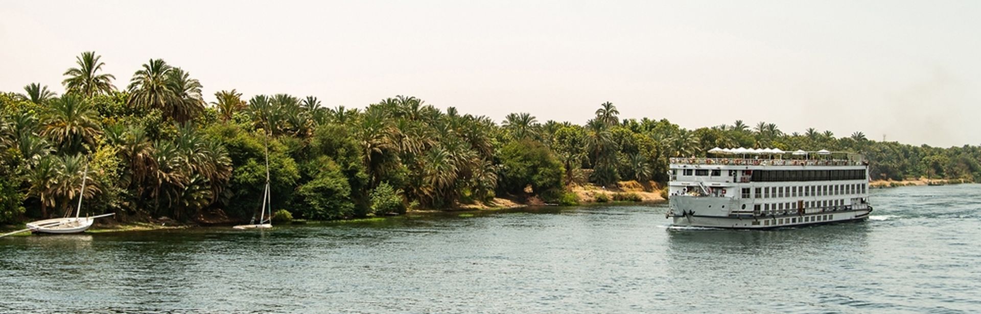 Flusskreuzfahrtschiff, mit Palmen im Hintergrud