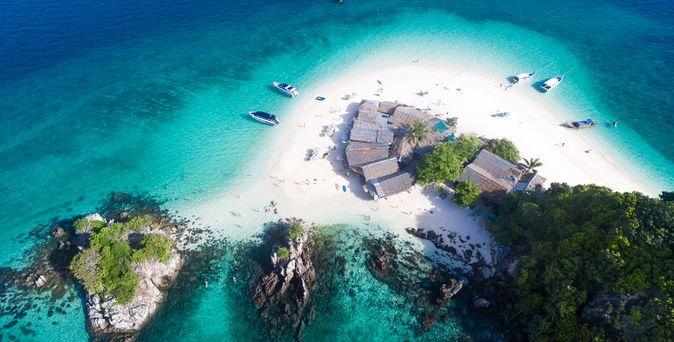 Luftaufnahme einer Insel mit Booten im türkisfarbenen Wasser 